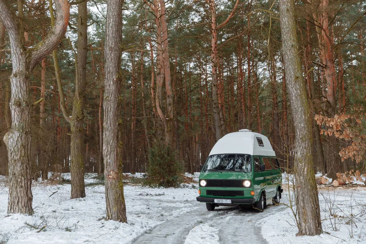 Ukážkový obrázok BookNoFees: Zelený kempingový autobus s vysokou strechou v zasneženom lese
