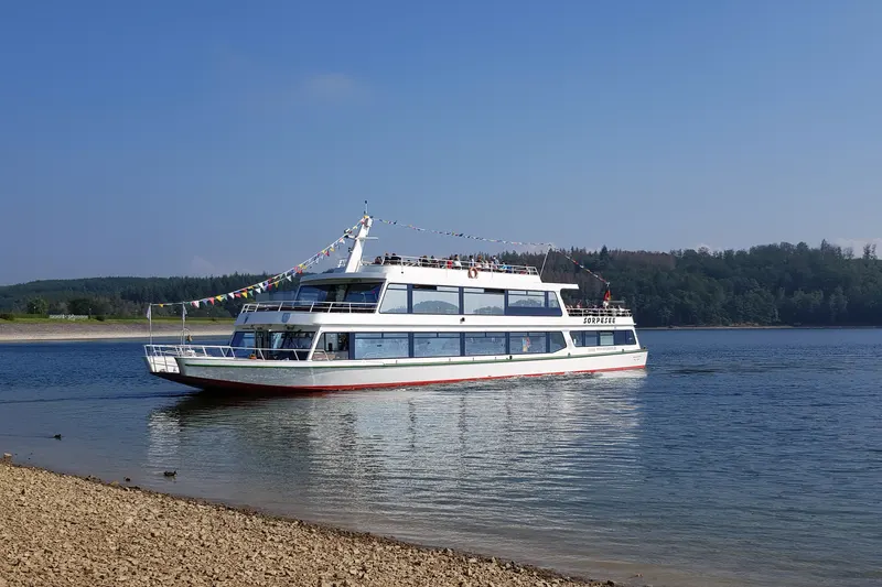 Výletná loď MS Sorpesee na jazere neďaleko Sundernu, s lesom na opačnom brehu