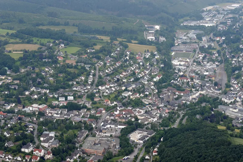 Mesto Sundern z vtáčej perspektívy, domy pozdĺž údolia Röhr medzi zalesnenými kopcami