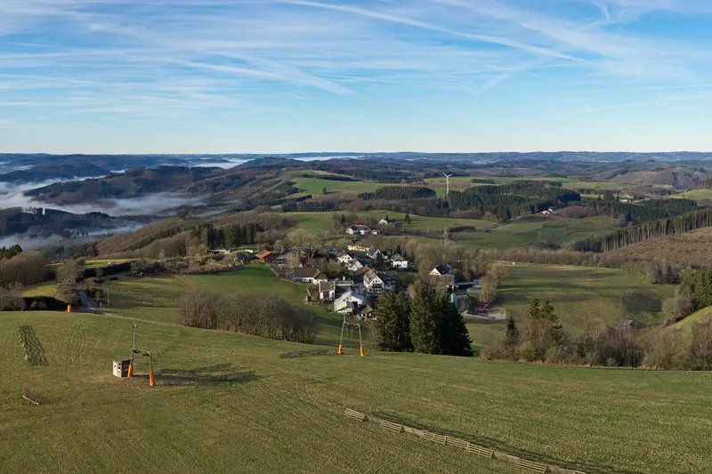 Wildewiese v kopcoch Sauerlandu, s lyžiarskym vlekom na lúke a dedinou pod ňou