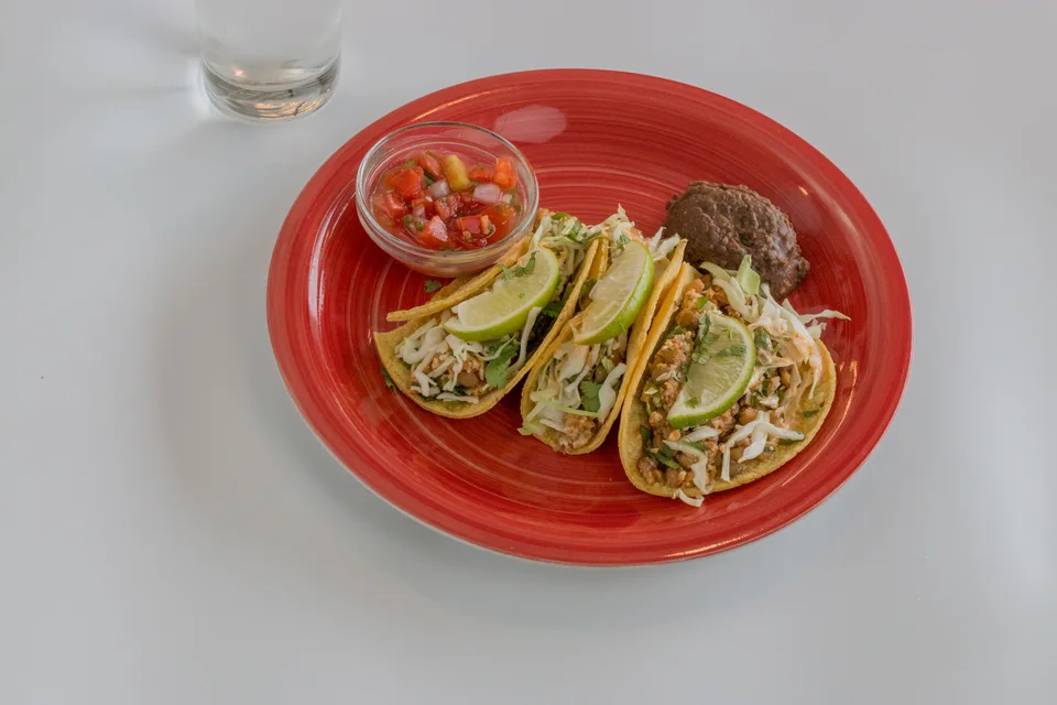 BookNoFees: Ukážková fotografia: Tri tacos ozdobené plátkami limetky so salsou na červenom tanieri